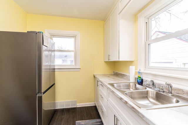 kitchen with visible vents, dark wood-type flooring, freestanding refrigerator, white cabinetry, and a sink