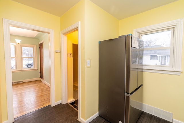 kitchen with dark wood-style floors, baseboards, visible vents, and freestanding refrigerator