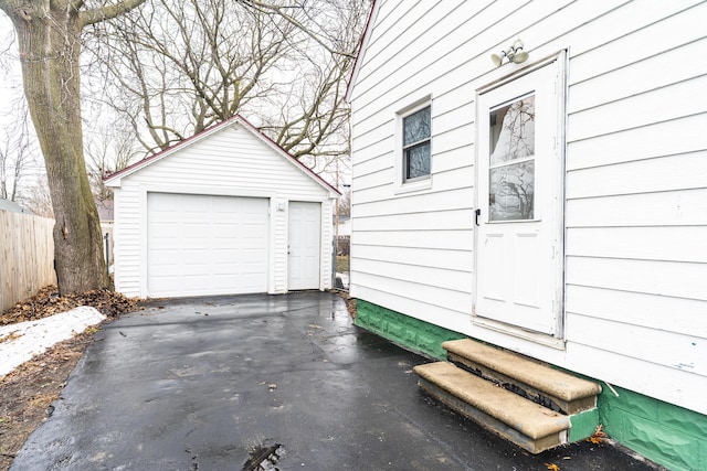 detached garage with aphalt driveway and fence