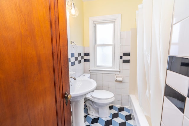 bathroom featuring toilet, a wainscoted wall, tile walls, and tile patterned floors