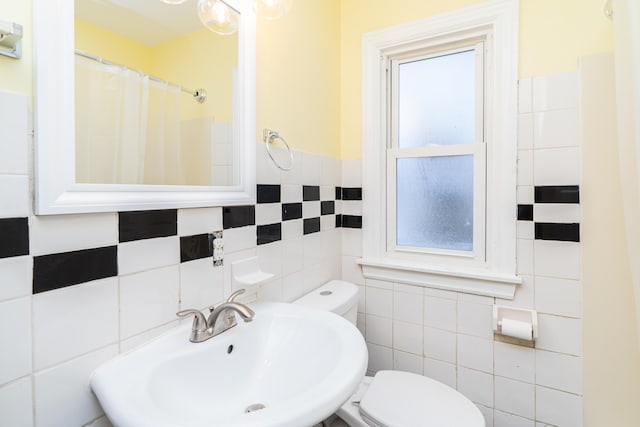 full bath with a shower with curtain, a sink, toilet, and tile walls