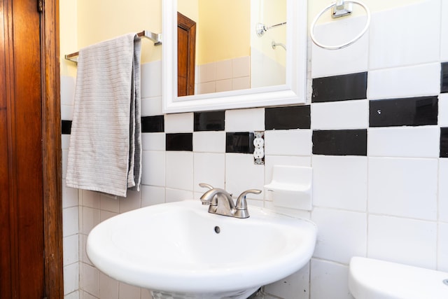 half bathroom featuring toilet, a sink, and tile walls