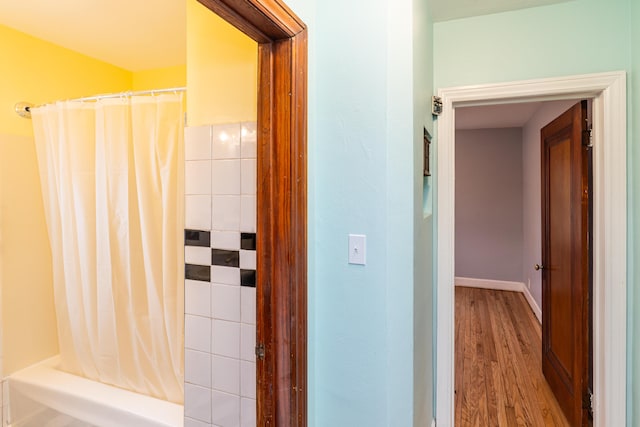 bathroom featuring baseboards, wood finished floors, and a shower with curtain