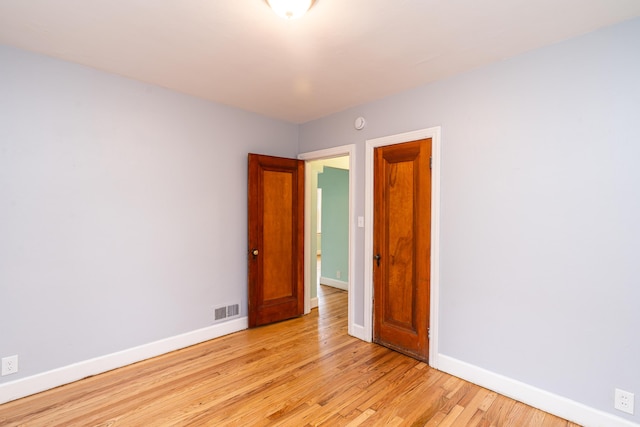 spare room featuring light wood-style floors, baseboards, and visible vents