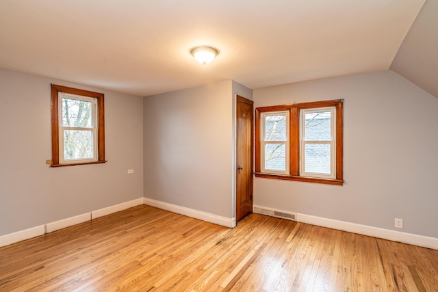 interior space featuring lofted ceiling, visible vents, light wood-style flooring, and baseboards