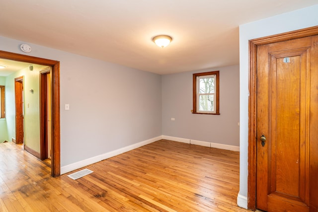 empty room featuring baseboards, visible vents, and light wood-style floors