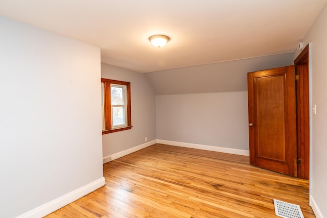 bonus room with light wood finished floors, baseboards, visible vents, and vaulted ceiling