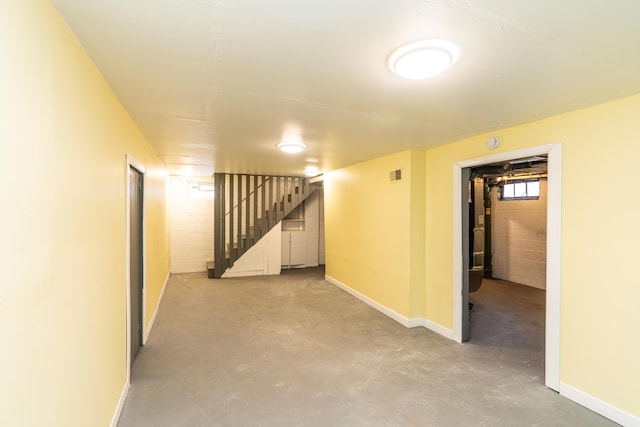 basement featuring concrete block wall, visible vents, baseboards, and stairs