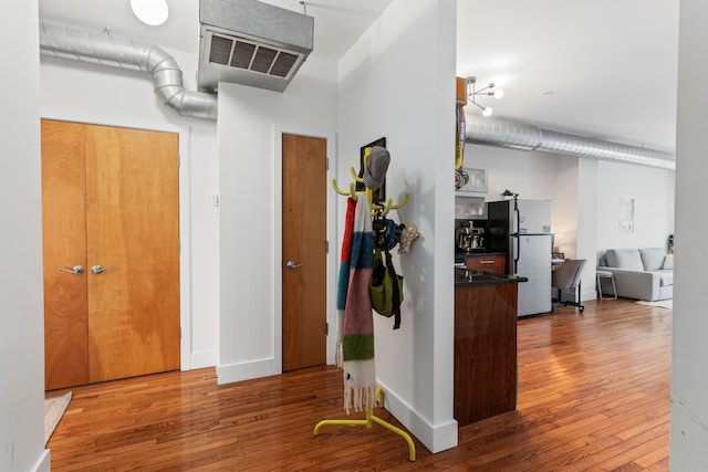 hallway with visible vents, baseboards, and hardwood / wood-style flooring