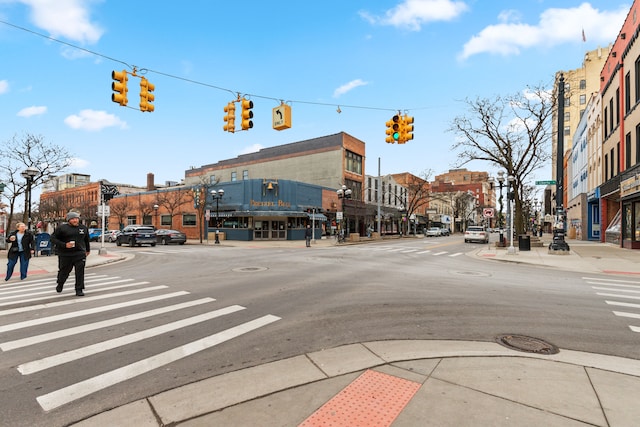 view of road featuring curbs, traffic signs, traffic lights, sidewalks, and street lighting