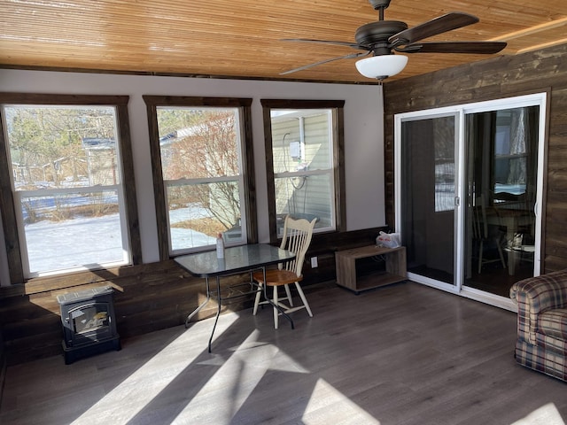 sunroom with a ceiling fan, wooden ceiling, and a wood stove