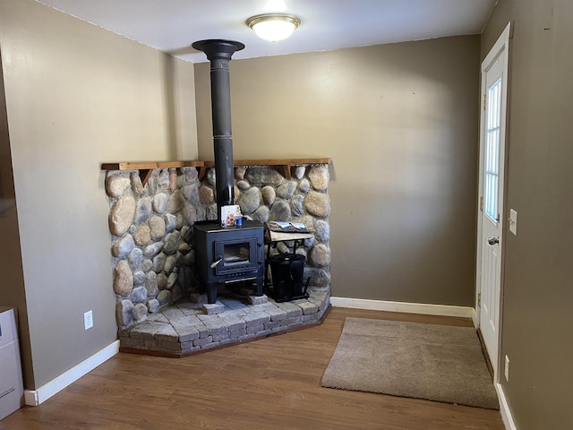 interior details featuring wood finished floors, a wood stove, and baseboards