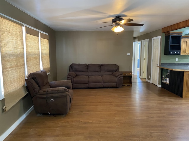 living room featuring ceiling fan, wood finished floors, and baseboards