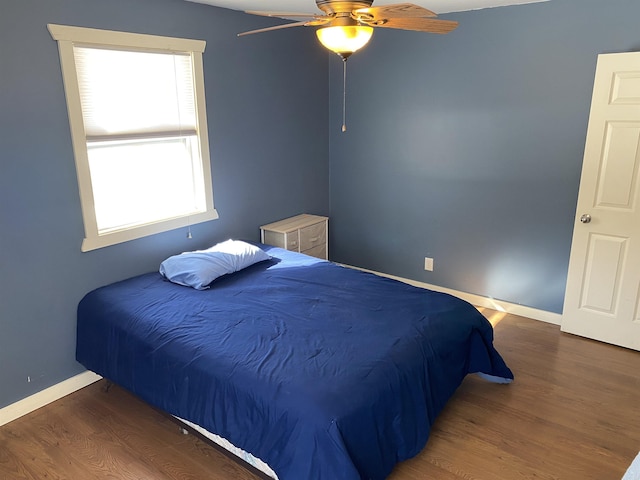 bedroom with ceiling fan, baseboards, and wood finished floors