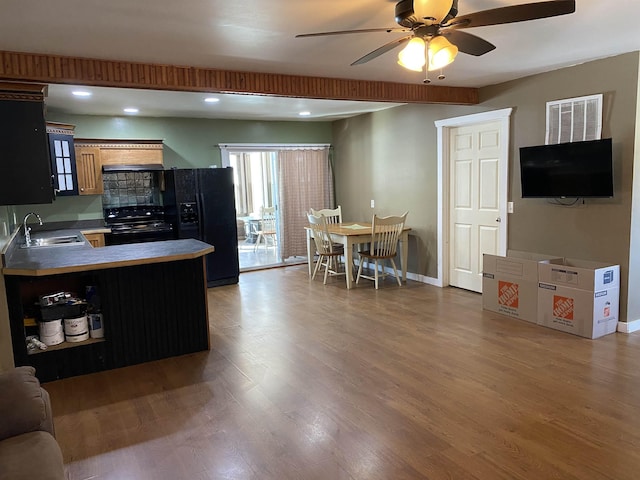 kitchen featuring baseboards, ceiling fan, wood finished floors, black appliances, and a sink