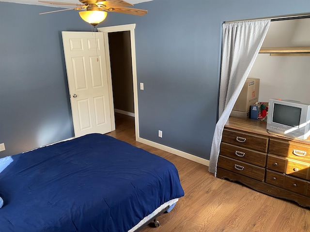 bedroom with light wood-type flooring, a closet, baseboards, and a ceiling fan