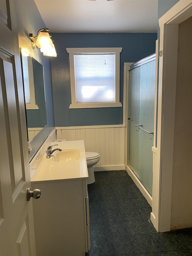 full bath with toilet, a stall shower, wainscoting, vanity, and tile patterned floors