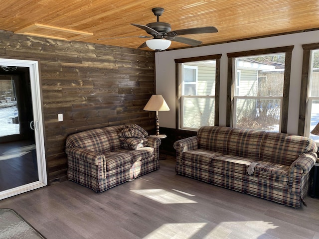 living room with ceiling fan, wood finished floors, wood ceiling, and wooden walls