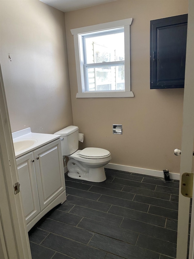 bathroom with wood finish floors, vanity, toilet, and baseboards