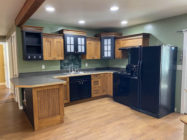 kitchen featuring open shelves, dark countertops, light wood-style flooring, a sink, and black appliances