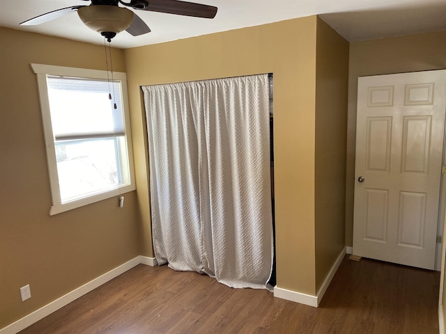 unfurnished room featuring ceiling fan, baseboards, and wood finished floors