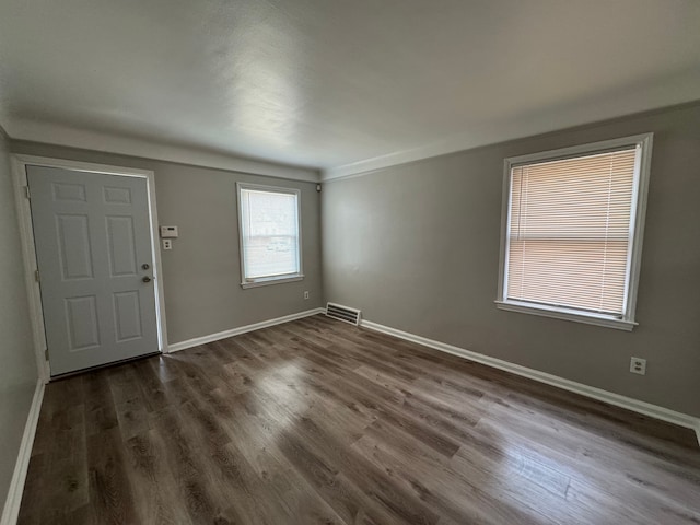 foyer with baseboards, visible vents, and dark wood-type flooring