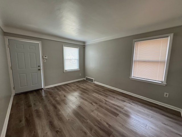 foyer entrance featuring dark wood-type flooring, visible vents, and baseboards