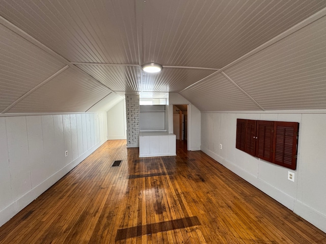 additional living space with lofted ceiling, visible vents, and hardwood / wood-style flooring