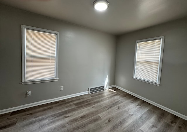 unfurnished room featuring wood finished floors, visible vents, and baseboards