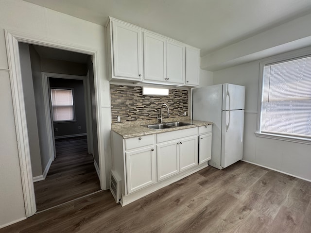 kitchen featuring dark wood-style flooring, tasteful backsplash, freestanding refrigerator, white cabinets, and a sink