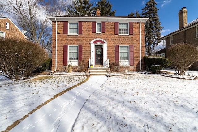 colonial home with brick siding and a chimney