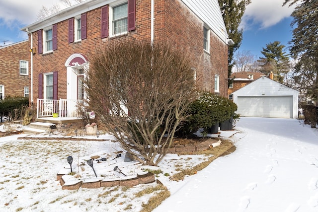 view of front of property featuring a detached garage, brick siding, and an outdoor structure