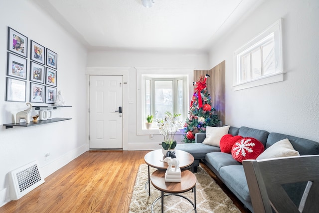 living room featuring light wood-style flooring, visible vents, and baseboards