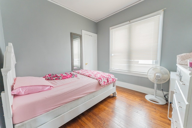 bedroom featuring ornamental molding, wood-type flooring, and baseboards