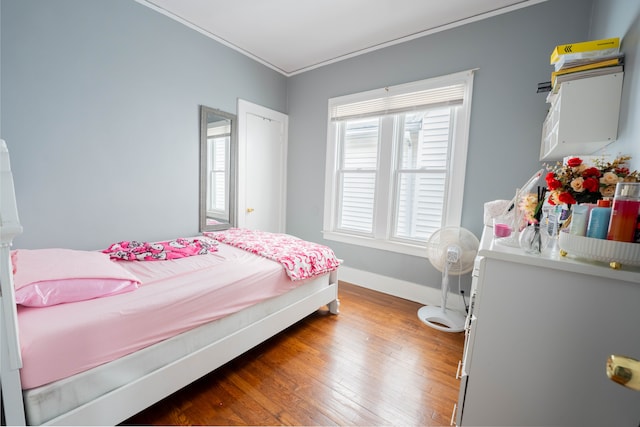 bedroom with ornamental molding, baseboards, and wood finished floors