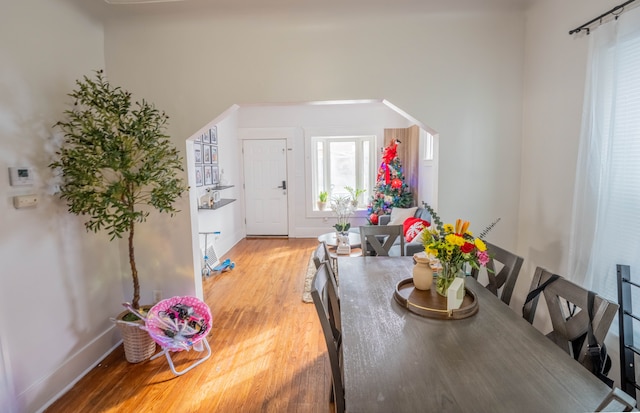 dining area with baseboards, arched walkways, and wood finished floors