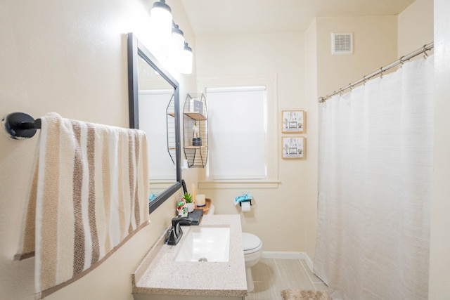 full bathroom with toilet, baseboards, visible vents, and vanity
