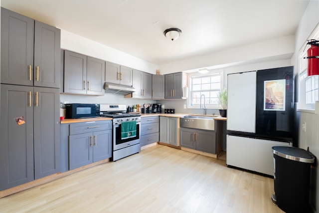 kitchen featuring gas range, gray cabinetry, under cabinet range hood, black microwave, and a sink