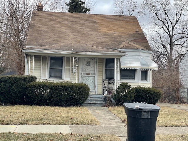 view of front of home featuring a chimney, a porch, and roof with shingles