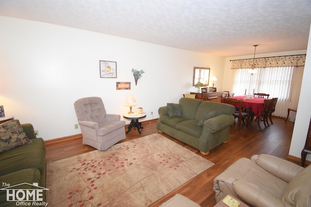 living area with a textured ceiling, baseboards, and wood finished floors