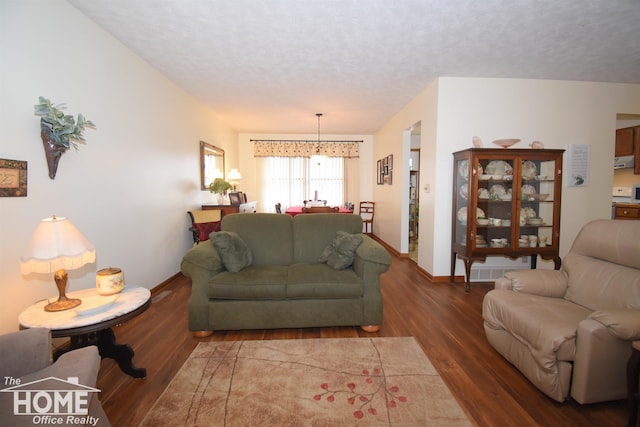 living room with an inviting chandelier, a textured ceiling, baseboards, and wood finished floors