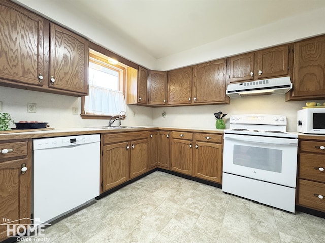 kitchen with under cabinet range hood, white appliances, a sink, light countertops, and brown cabinets