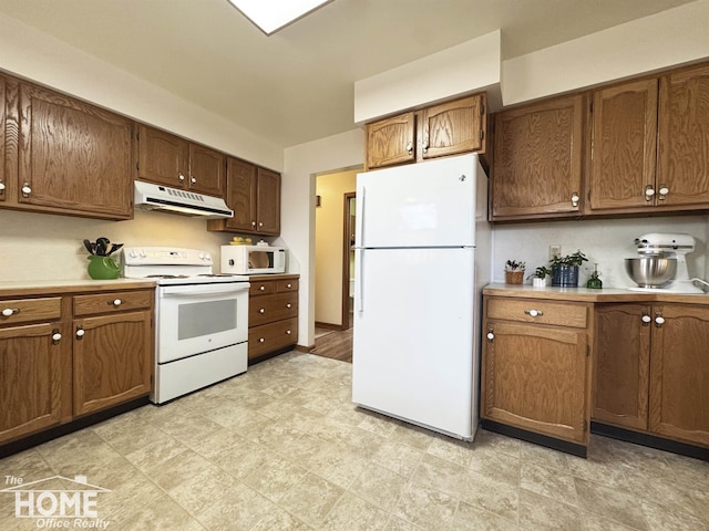 kitchen with white appliances, under cabinet range hood, light countertops, and brown cabinetry