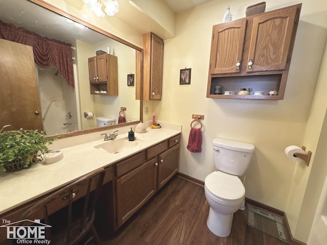 bathroom with baseboards, a shower, toilet, wood finished floors, and vanity