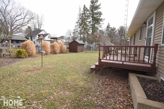 view of yard with a deck, an outdoor structure, fence, a residential view, and a storage unit