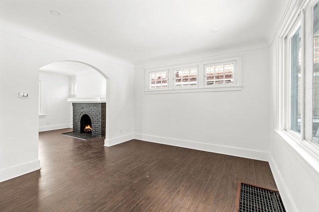 unfurnished living room with dark wood-style flooring, visible vents, a fireplace, and baseboards