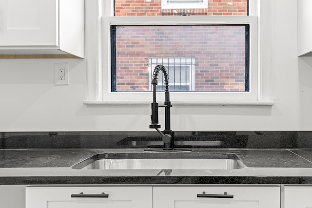 kitchen with dark countertops, white cabinets, and a sink