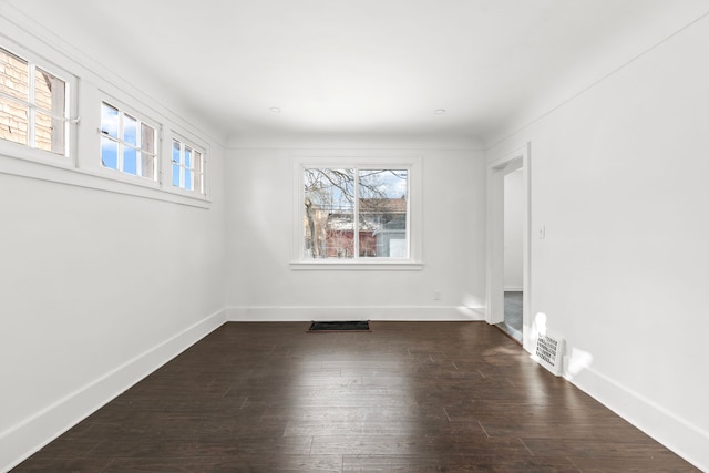 unfurnished room featuring dark wood-style floors, visible vents, and baseboards