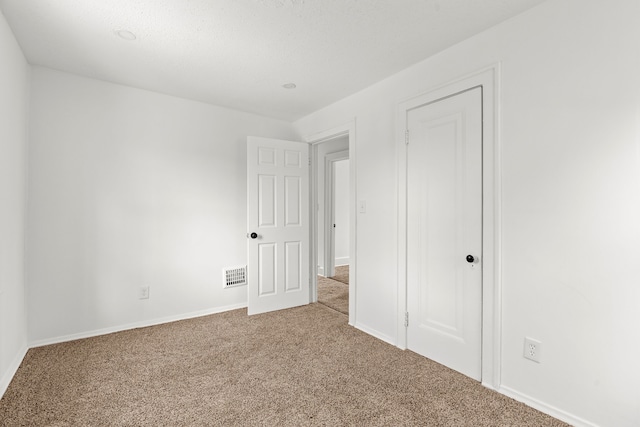 unfurnished bedroom with carpet floors, visible vents, and baseboards