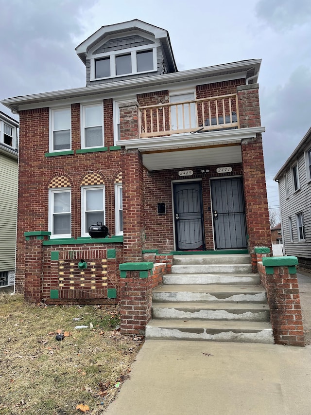 view of front facade with brick siding and a balcony